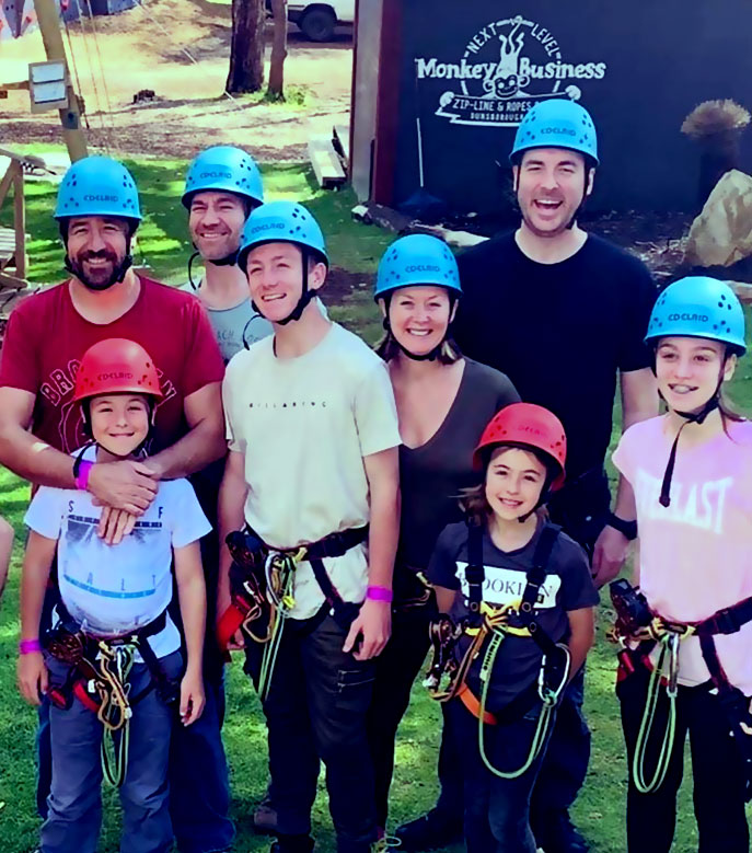 Two happy families in hemlets and safety gear about to go on the ropes course